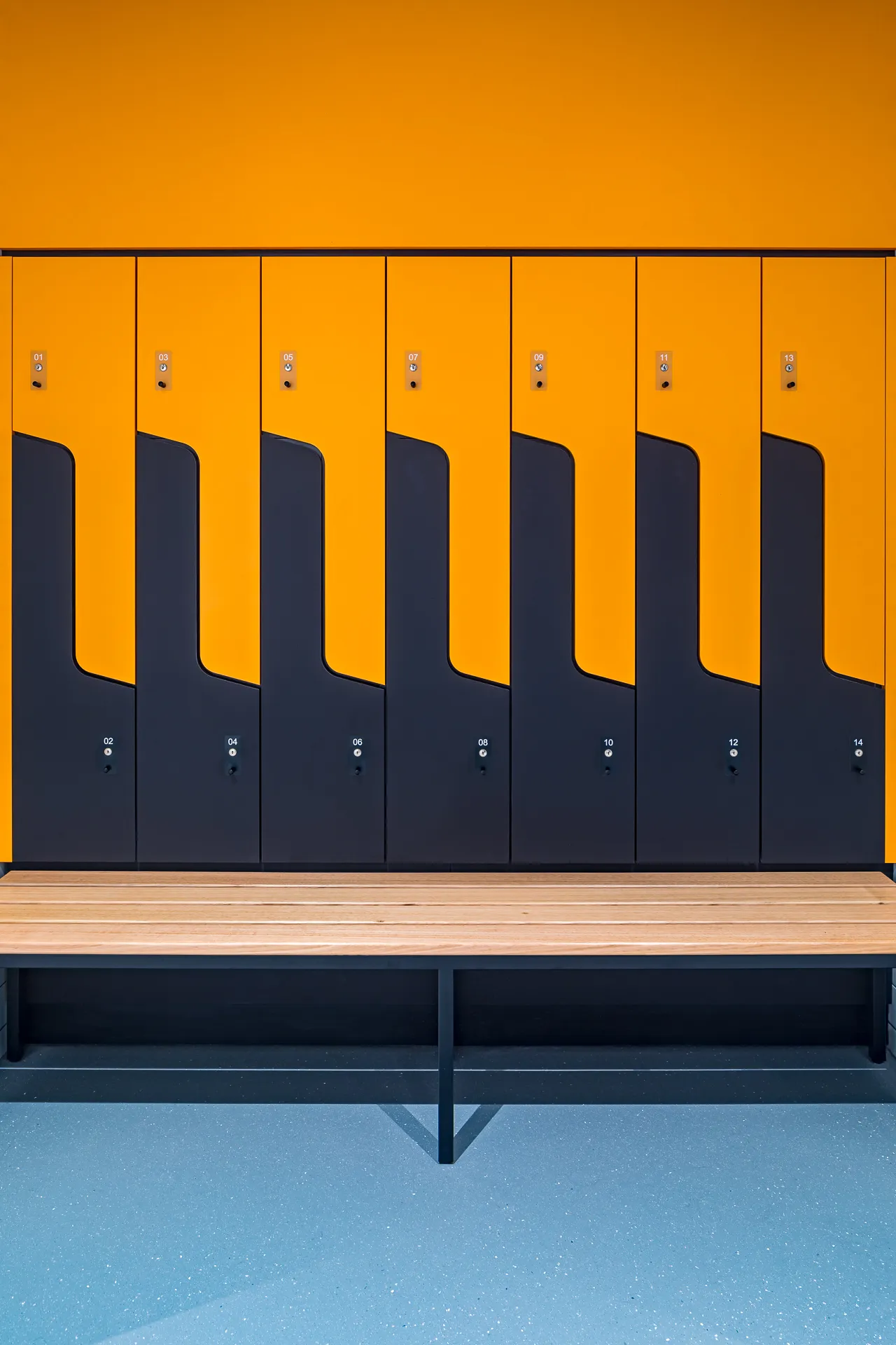 Orange and black player lockers with bench seating — West Tigers Centre of Excellence